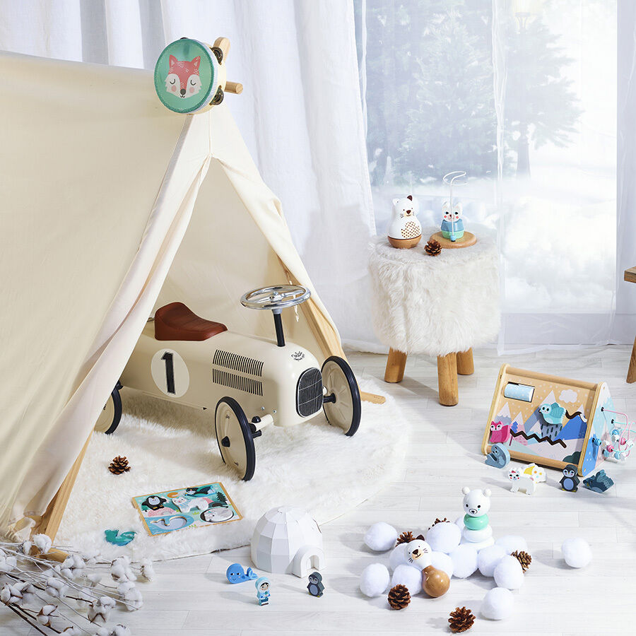 Spielzeug Vintage-Auto im Kinderzimmer, umgeben von einer Spielzeug-Ecke mit Zelt, hellen Stoffen und Holzboden.