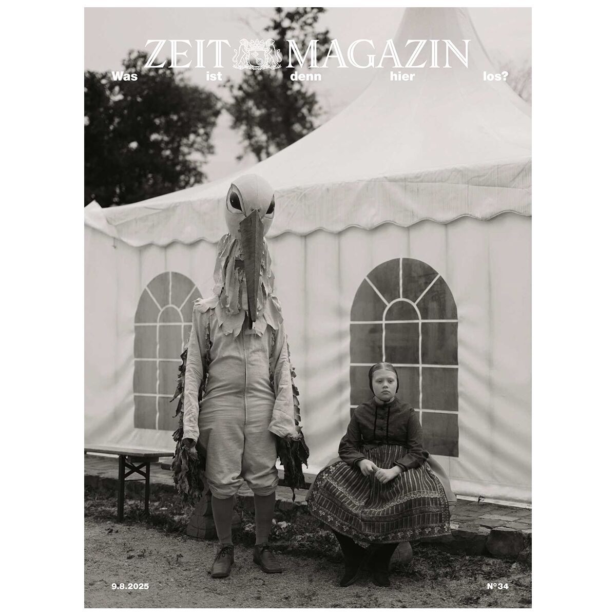 Titelseite der Zeitschrift DIE ZEIT Magazin Ausgabe 34/2025 mit einem in einem Storchkostüm verkleideten Erwachsenen und einem Mädchen in traditioneller Kleidung vor einem weißen Zelt; das Bild ist in Schwarzweiß gehalten.