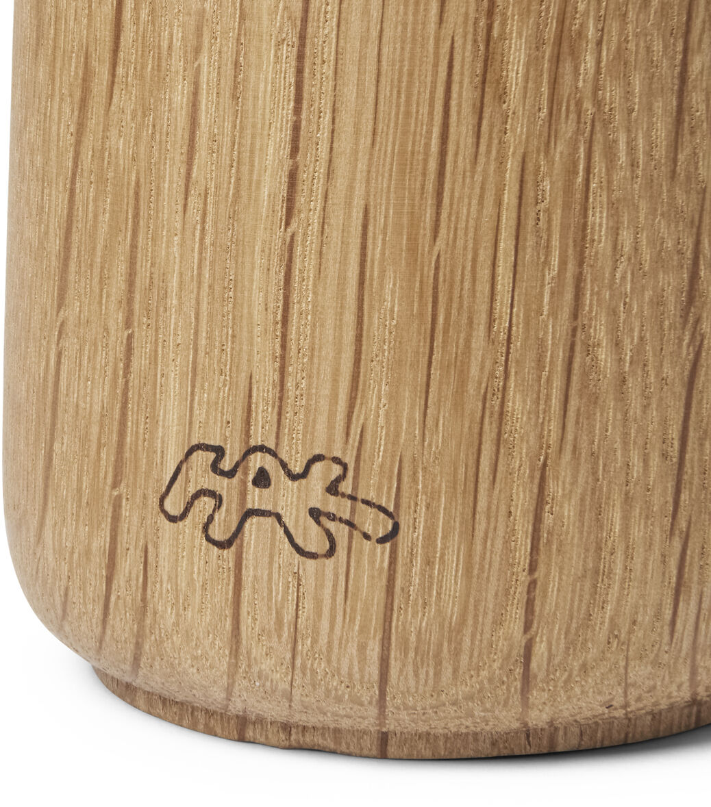 Nahaufnahme einer Gewürzmühle aus hellem Holz mit einer feinen Maserung und einem dezenten Logoaufdruck. Die Mühle hat ein schlichtes, modernes Design und steht auf einer weißen Oberfläche.