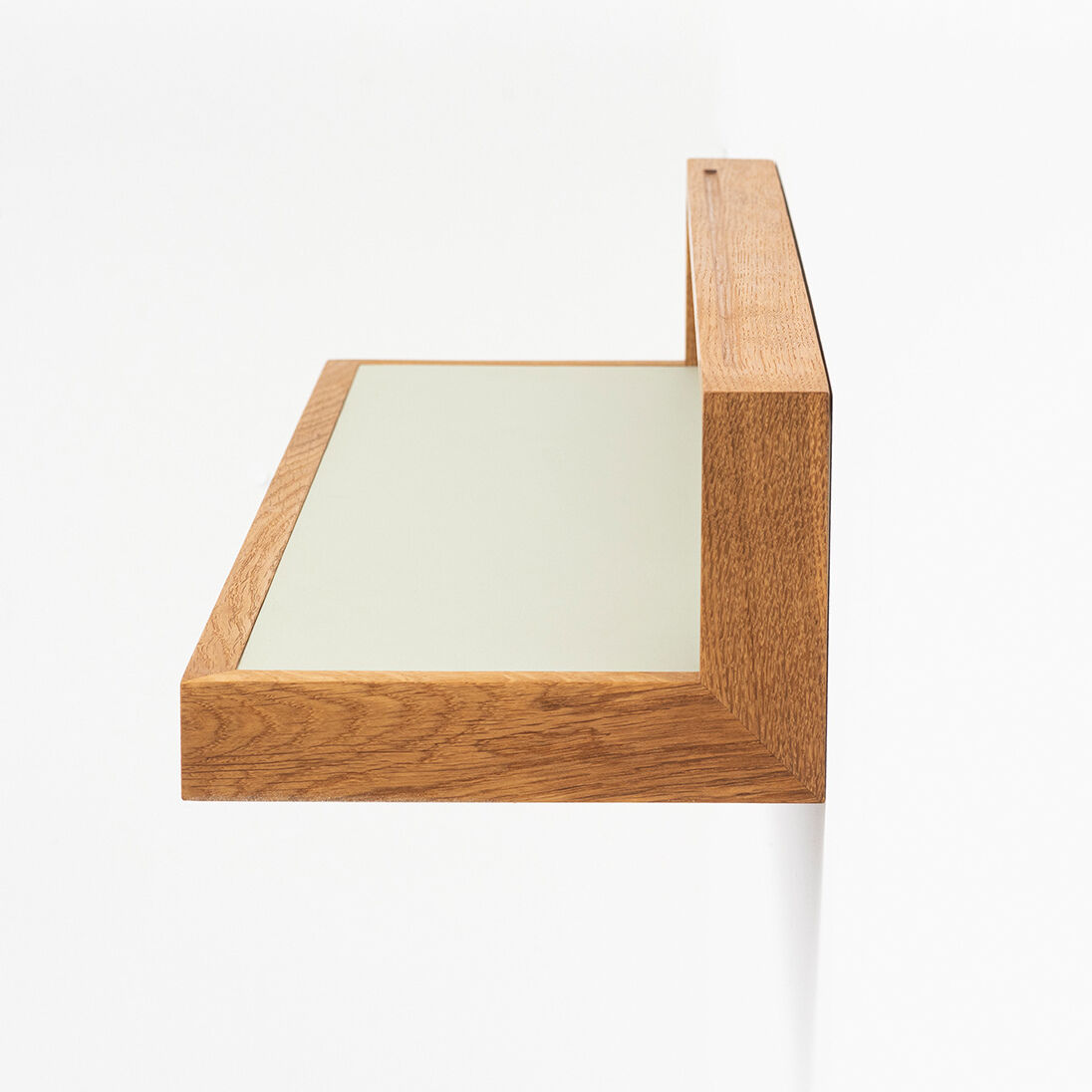 Seitliche Ansicht eines schlanken Ablagebords (Modell »buck« pistazie von das kleine b) aus geölter Eiche, Oberfläche mit pistaziengrünem Möbellinoleum. Das Regal ist an der Wand montiert, wirkt minimalistisch und modern. Klare Linien, elegantes Design, hochwertige Verarbeitung.