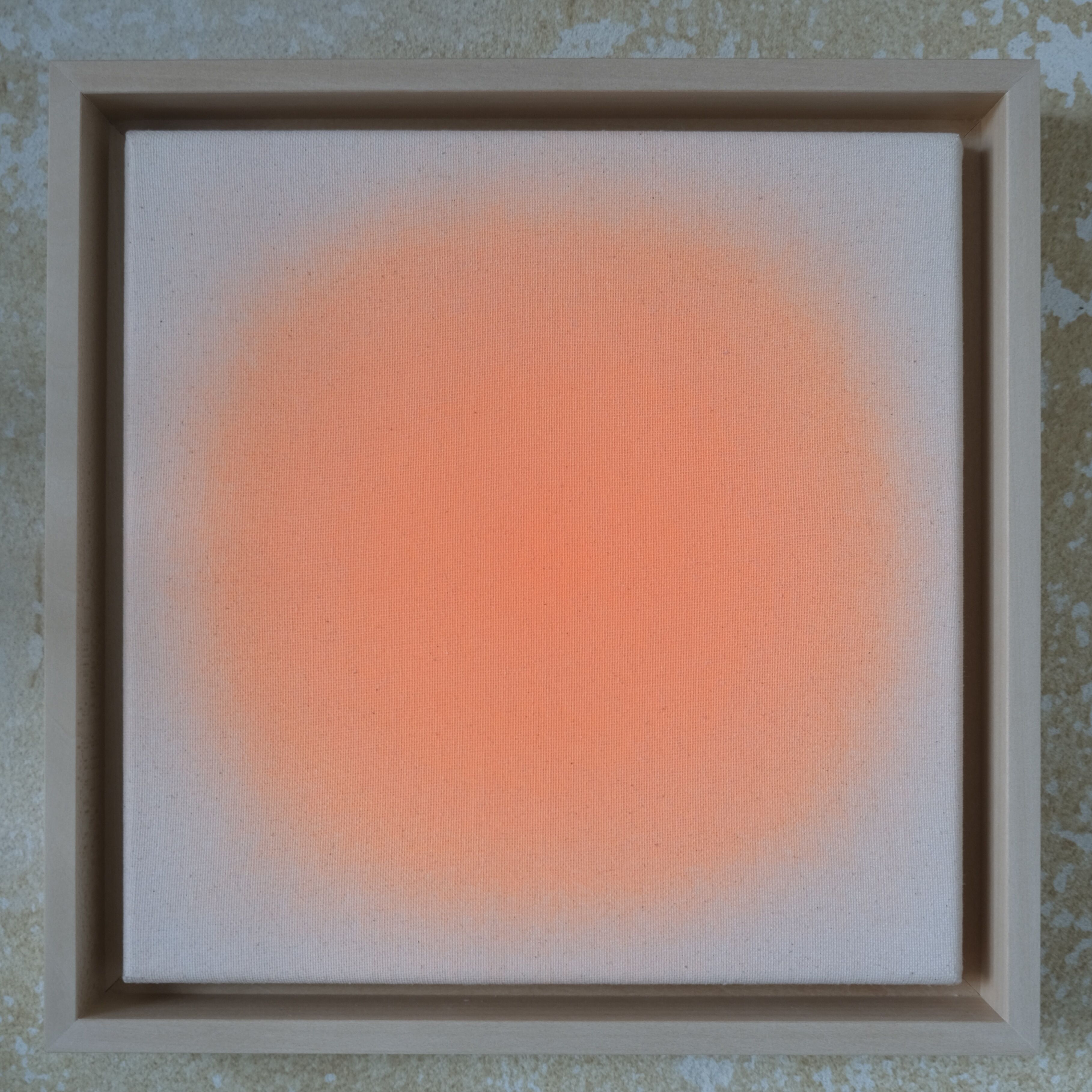 Quadratisches Kunstwerk in Lindenholzrahmen: Eine zarte, leuchtend orange-rosafarbene Kreisfläche auf naturbelassener, beige wirkender Leinwand, die in einen sanften Farbverlauf übergeht. Der massive Rahmen weist einen natürlichen Holzton auf. Das Gesamtbild wirkt modern, minimalistisch und freundlich.