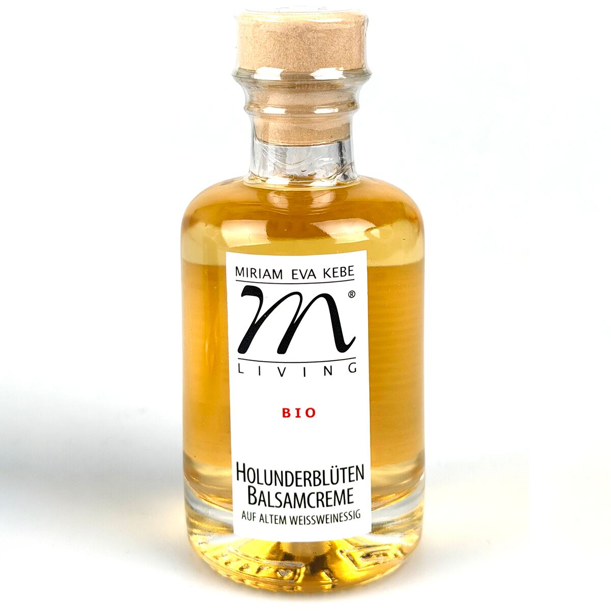 Eine elegante Glasflasche mit hellgelber Flüssigkeit, verschlossen mit einem Holz- und Korkverschluss. Das Etikett zeigt die Marke 'MIRIAM EVA KEBE', die Produktbezeichnung 'HOLUNDERBLÜTEN BALSAMCREME', Bio-Logo und schwarze Schrift auf weißem Hintergrund.