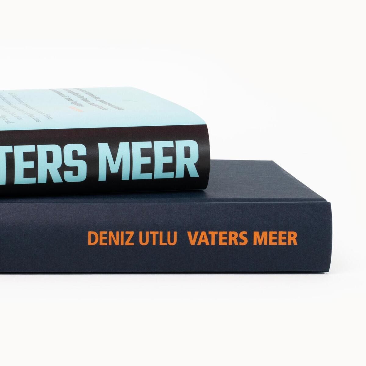 Zwei aufeinander gestapelte Bücher mit dem Titel 'Vaters Meer' von Deniz Utlu. Das obere Buch hat einen hellblauen Buchrücken mit weißen Buchstaben, das untere Buch hat einen dunkelblauen Buchrücken mit orangefarbenen Buchstaben.