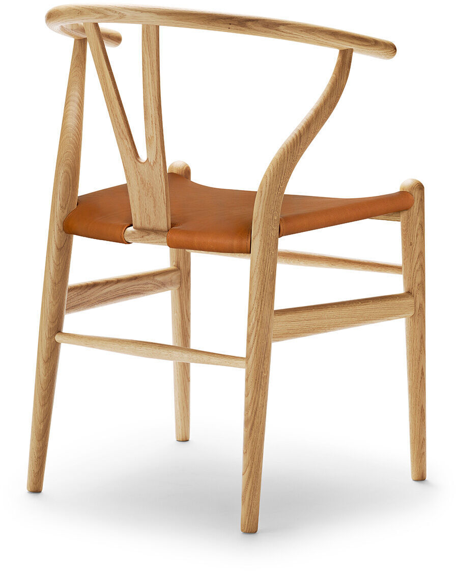 Ein Wishbone Chair mit einem Gestell aus Eichenholz und einer Sitzfläche aus Leder. Der Stuhl zeigt ein modernes, minimalistisches Design, ideal für Esszimmer oder Wohnräume.