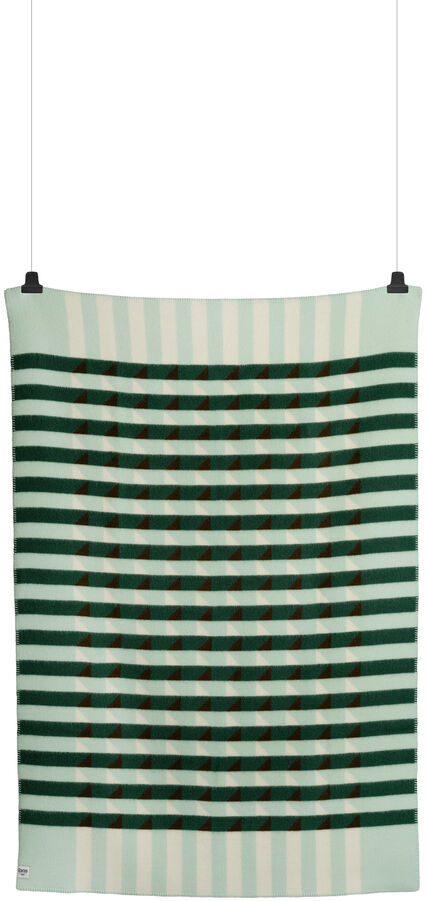 Lammwolldecke »KVAM« mit grün-beige gestreiftem Muster, aufgehängt und perfekt für gemütliche Winterabende.