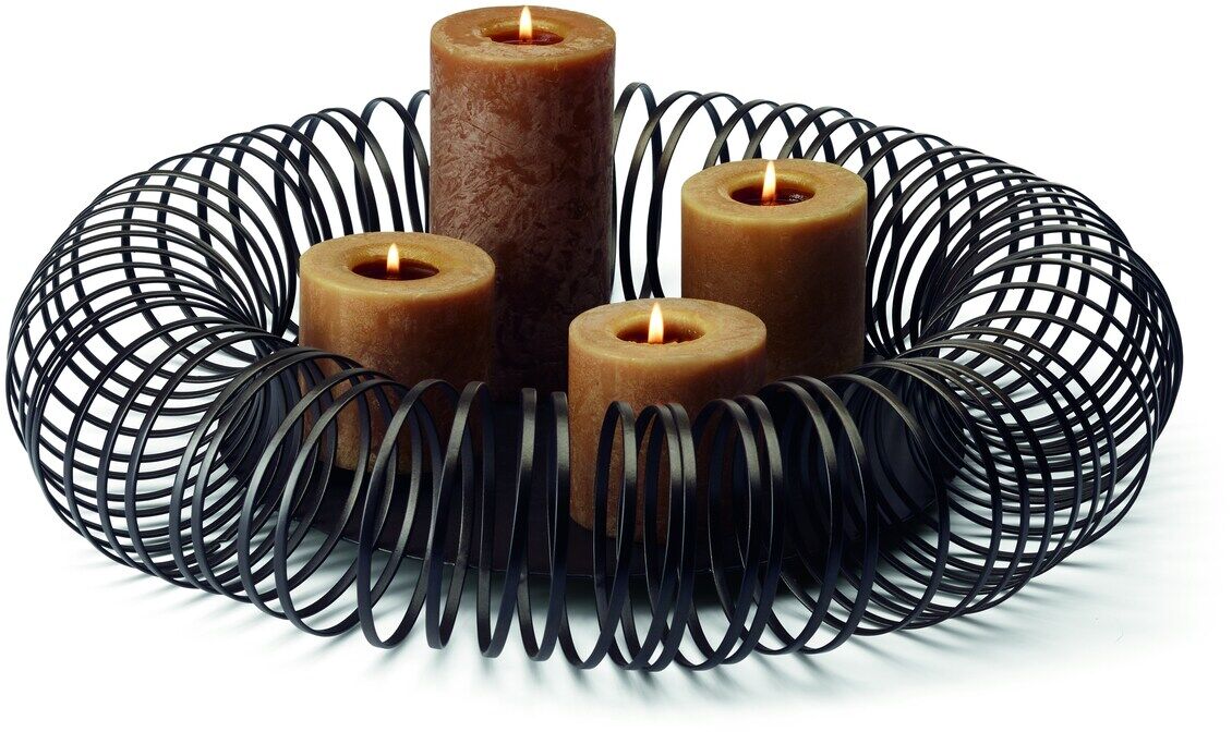 Eine moderne Adventsschale aus schwarzem Metall mit vier brennenden Kerzen in verschiedenen Größen. Die Kerzen sind dunkelbraun und verleihen dem Arrangement eine gemütliche, festliche Atmosphäre.
