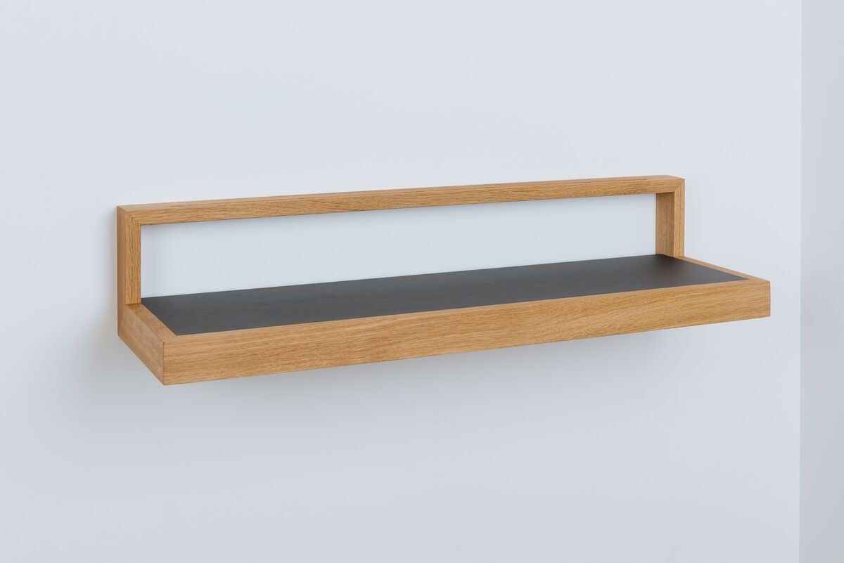 Ein modernes Wandregal mit schwarzem Ablageboden und einem Rahmen aus hellem Holz. Das Regal hat ein minimalistisches Design und ist freischwebend an der Wand montiert.