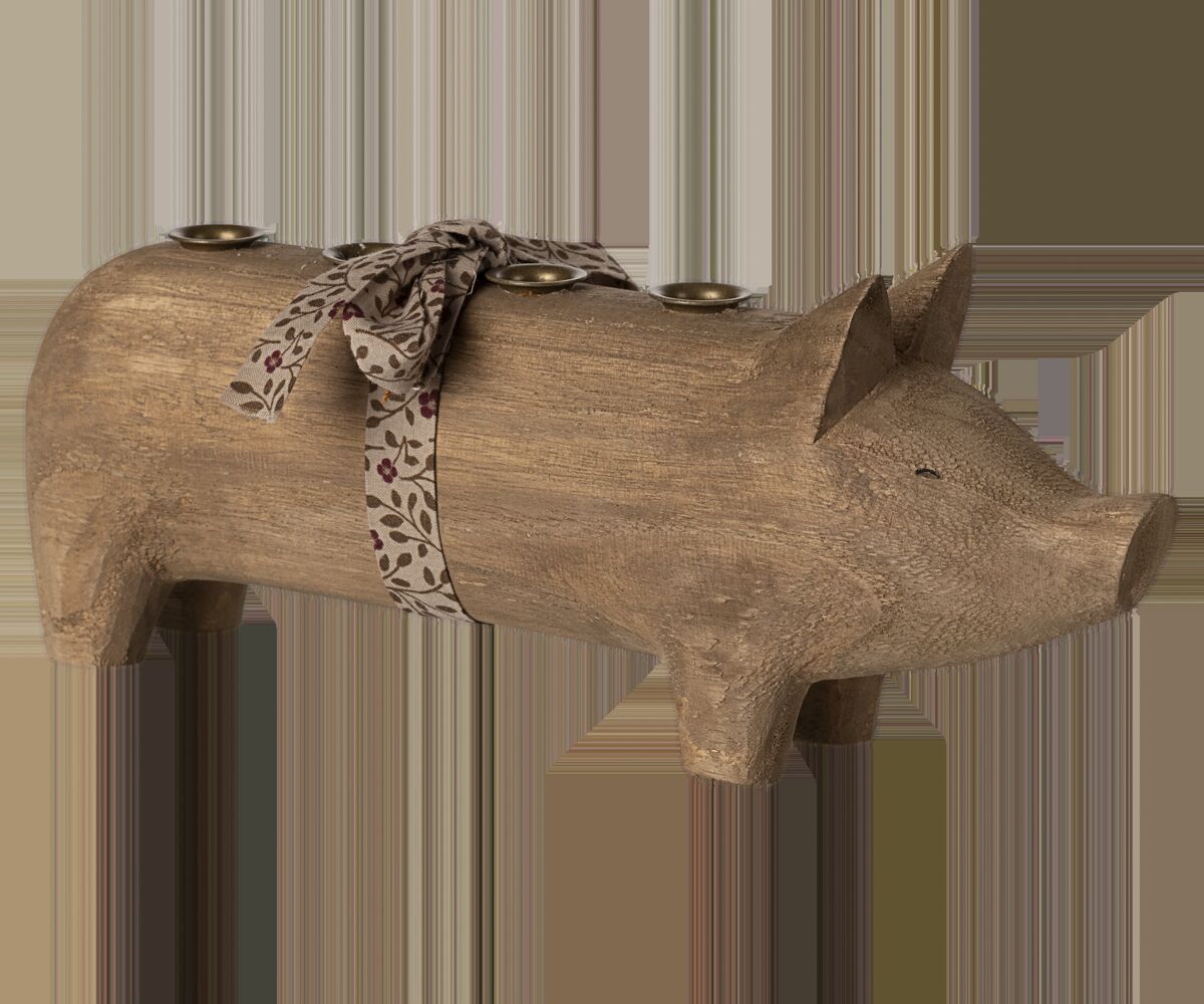 Großer Kerzenständer in Form eines Schweins aus naturfarbenem Holz mit vier Kerzenhaltern und einer dunkelroten Schleife mit Blattmuster um den Körper, rustikales Dekorationsobjekt für den Tisch.