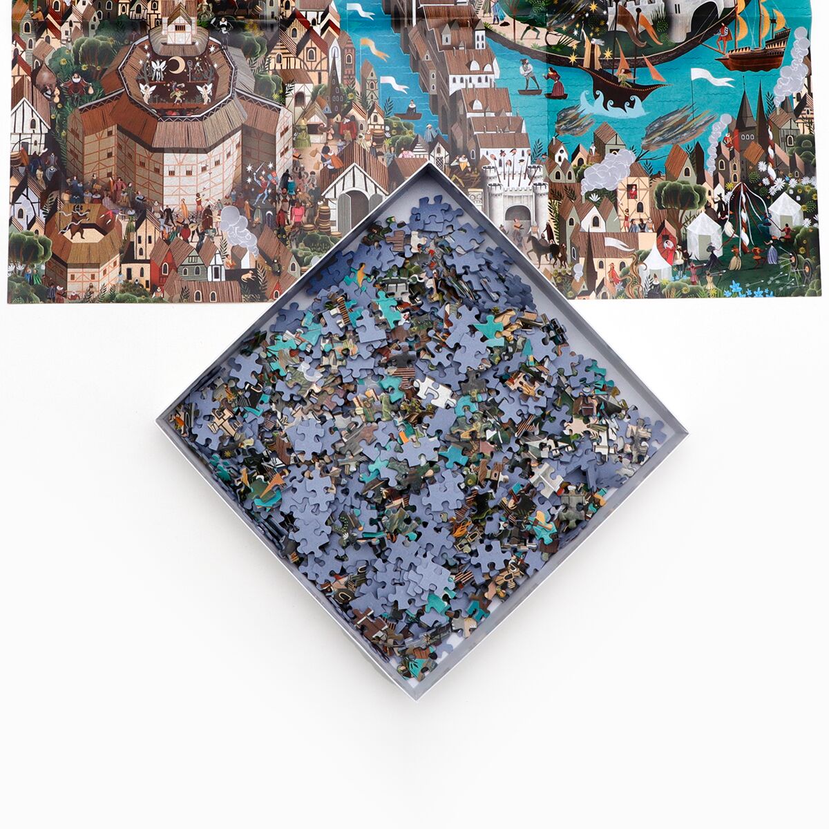 Das Bild zeigt das Puzzle »Shakespeares Welt« von Laurence King Verlag. Im Vordergrund ist die geöffnete Puzzlekiste mit unsortierten, überwiegend blauen und braunen Teilen zu sehen. Im Hintergrund ist ein detailliertes Motiv von Shakespeares London abgebildet, mit berühmten Gebäuden, Menschen und vielzähligen Details.