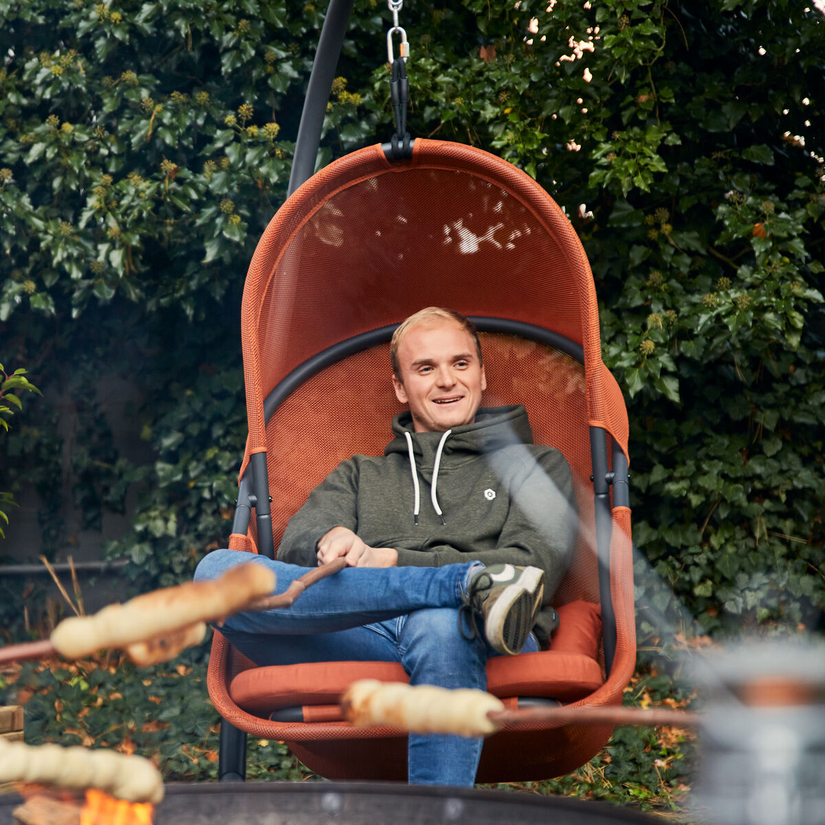 Detailreicher Hängesessel »Yobaya« von Sienagarden, Gestell aus pulverbeschichtetem Stahl in dunklem Grau, Bezug aus offenporigem Polyester AIR MESH in relaxed red. Der großzügige, ovale Korb ruht auf einem stabilen Gestell, wirkt modern und einladend, geeignet für den Garten oder Balkon.