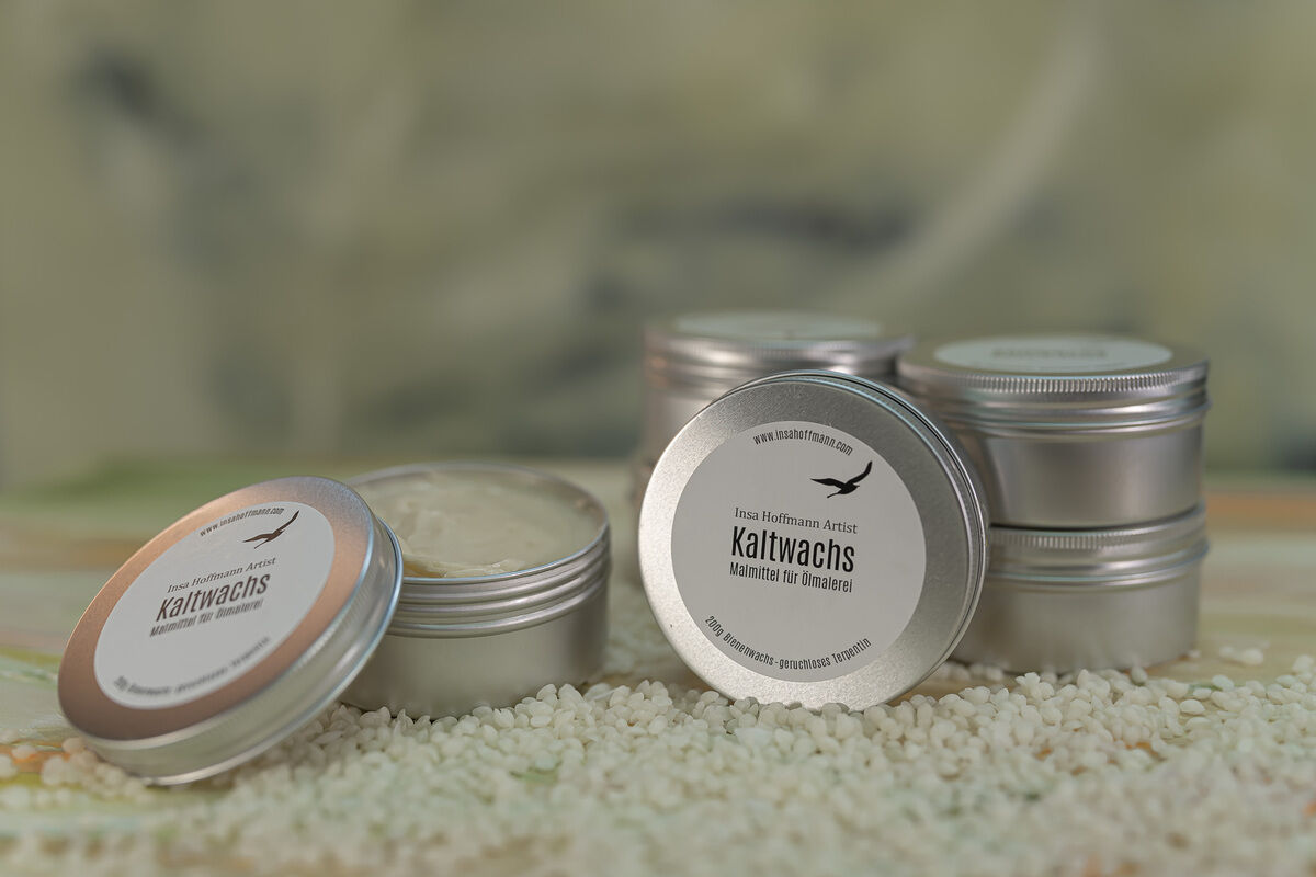 Eine Gruppe von silbernen Dosen mit der Aufschrift 'Kaltwachs' auf einer Oberfläche, umgeben von kleinen weißen Körnern, mit einer weichen, unscharfen Hintergrund. Produkt ZEIT-Sonderedition Kunstkurs: Insa Hoffmann - Kaltwachs und Ölfarbe.