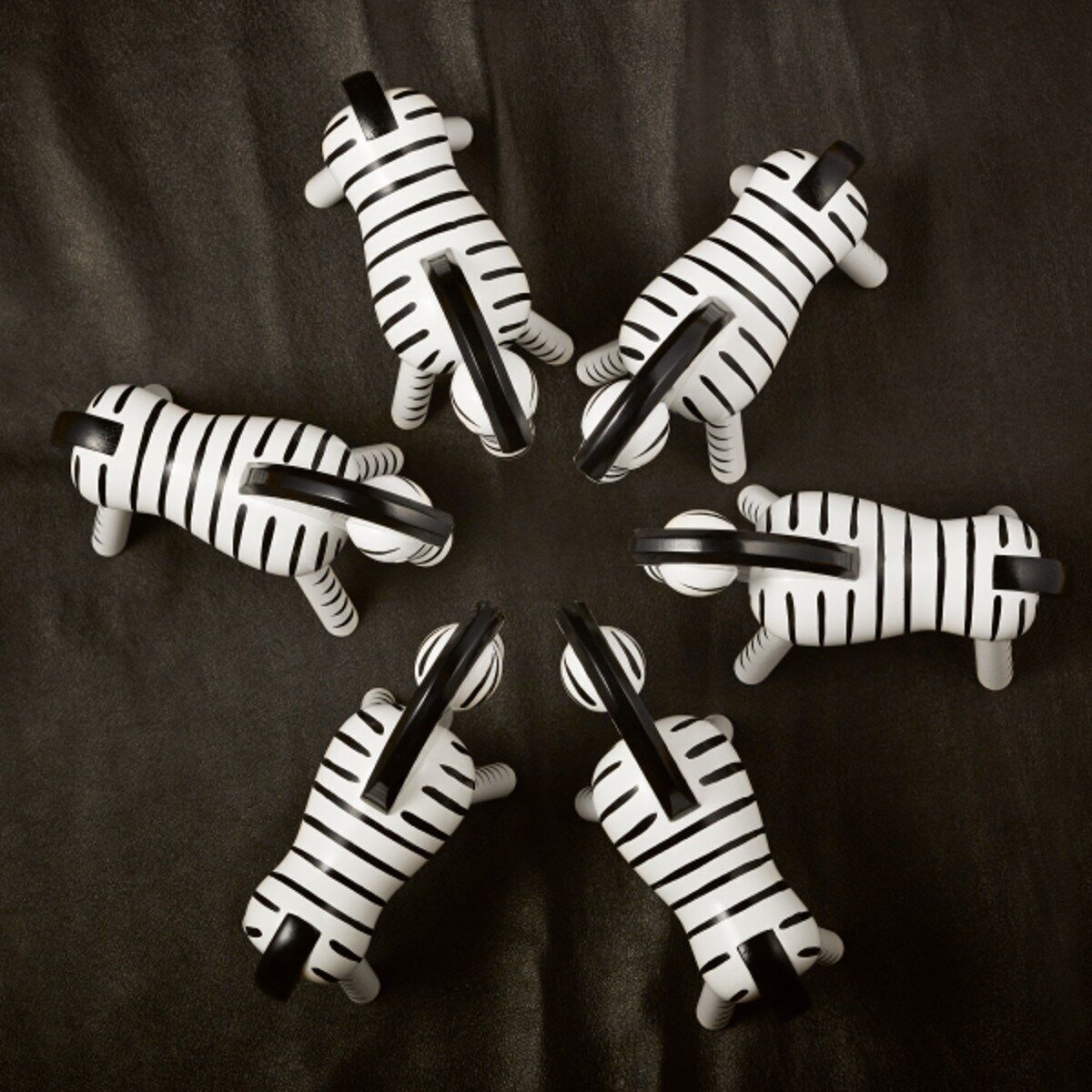 Sechs kleine Holzfiguren im Design von Zebras von Kay Bojesen, aufgestellt in einem Kreis auf einem dunklen Hintergrund.
