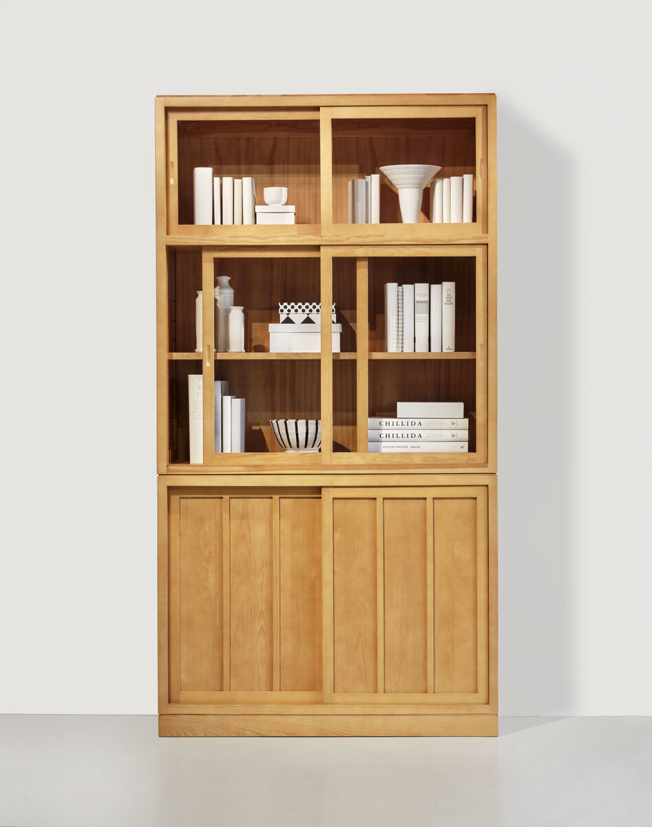 Holzvitrine mit mehreren Regalböden und dekorativen Elementen wie Bücher und Vasen. Die Türen der Vitrine bestehen teils aus Holz, teils aus Glas.
