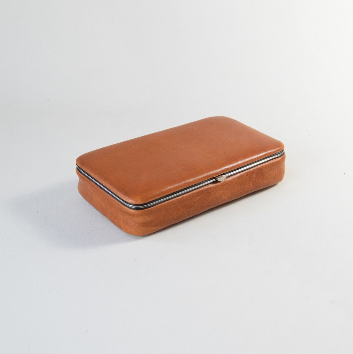 Eine elegante Utensilienbox aus Leder in Brauntönen. Die Box hat eine rechteckige Form und glänzt durch ihr modernes, minimalistisches Design. Ideal für die Aufbewahrung von Bürobedarf oder persönlichen Gegenständen.