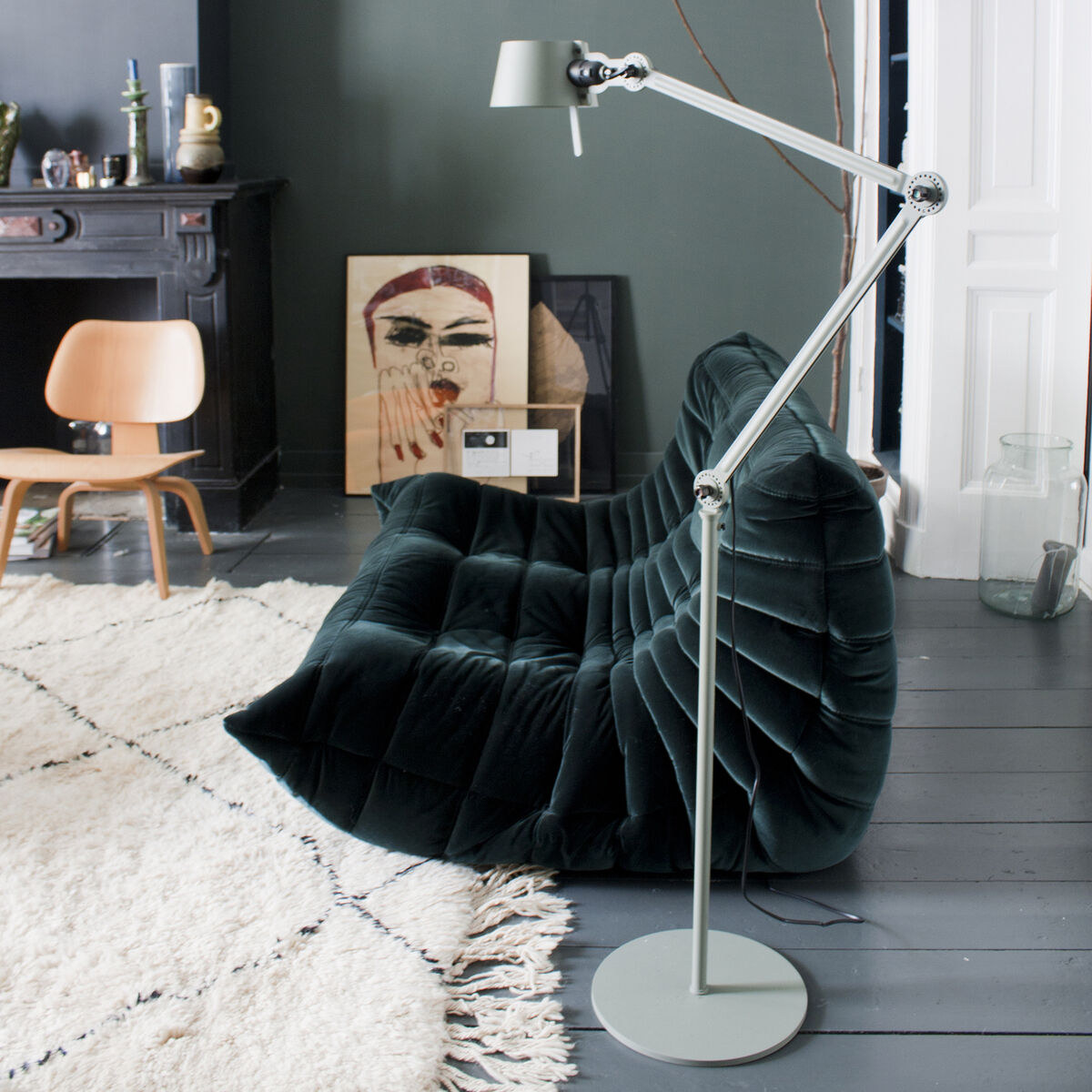 Eine moderne, zweifarbig abgesetzte Stehlampe BOLD (2arm) neben einem grünen Samtsofa in einem stilvoll eingerichteten Wohnzimmer mit einem grauen Boden, einem schwarz-weißen Teppich und grünen Wänden.