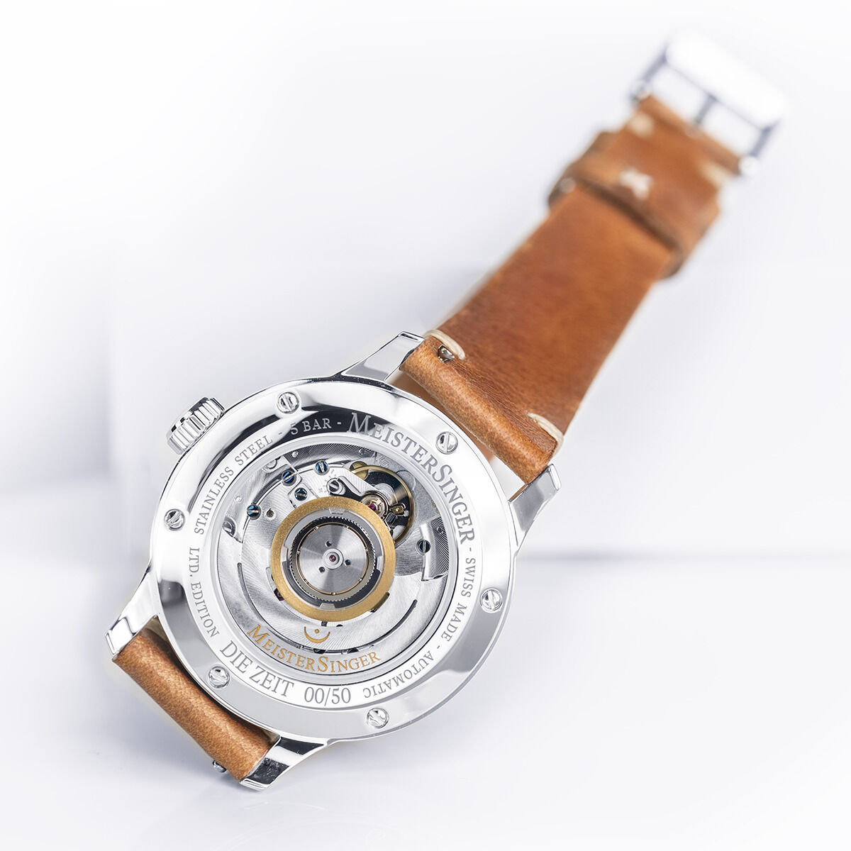 ZEIT-Sonderedition »Perigraph« Uhr von MeisterSinger mit einem braunen Lederarmband und einem silbernen Gehäuse. Die Rückseite des Uhrwerks ist sichtbar durch ein transparentes Zifferblattgedeck.