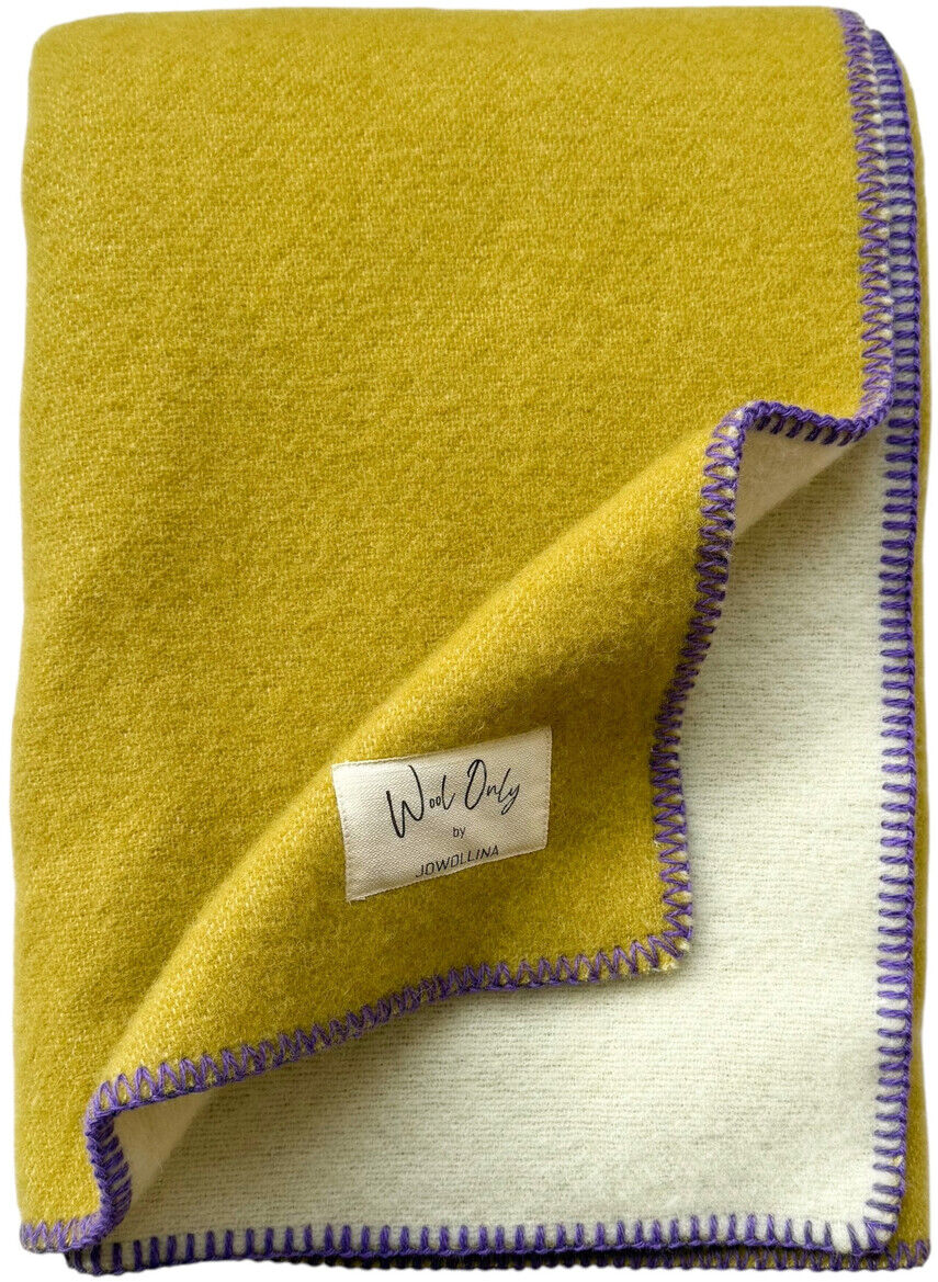 Gelbe Decke mit violetter Umrandung, die aus zwei unterschiedlichen Stoffseiten besteht, gezeigt in zusammengefalteter Form.