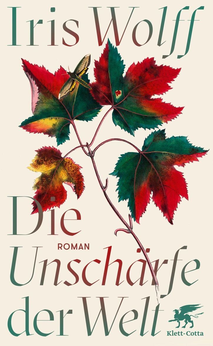 Das Bild zeigt das Buchcover des Romans 'Die Unschärfe der Welt' von Iris Wolff. Auf dem Cover sind grüne und rote Herbstblätter abgebildet, in dessen Zentrum ein zarter Schmetterling sitzt. Der Hintergrund des Covers ist cremefarben. Unten rechts ist das Logo des Verlags Klett-Cotta zu sehen.