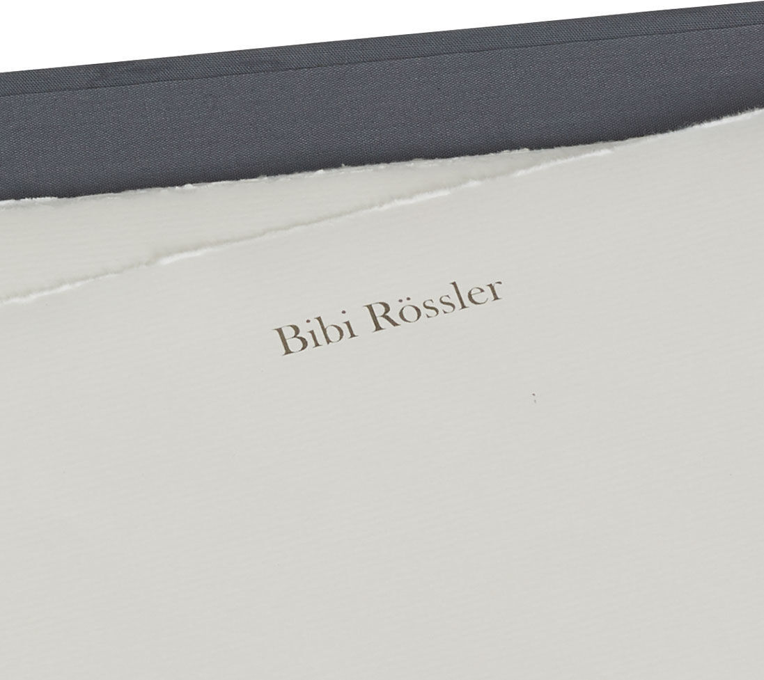 Briefpapiermappe mit edlem Büttenpapier und dem Namen 'Bibi Rössler' auf gedrucktem Papier. Sichtbare Farben sind Weiß, Grau und Schwarz.