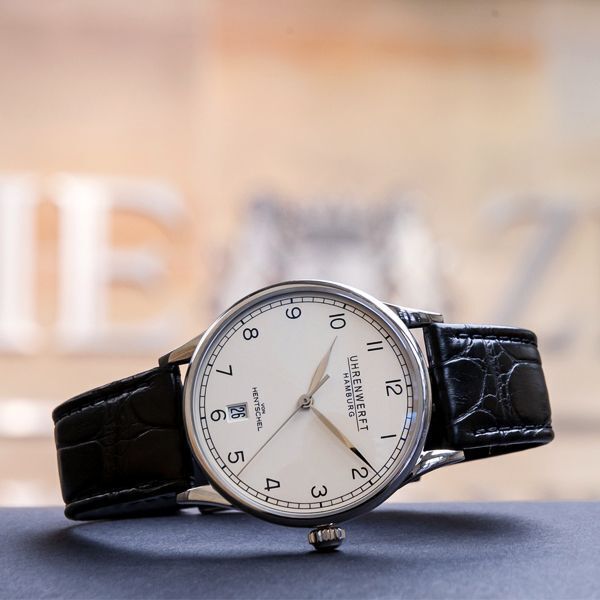 Eine Luxusuhr mit schwarzem Lederarmband und weißem Zifferblatt. Die Uhr zeigt die Uhrzeit analog und hat ein schlichtes, elegantes Design. Perfekt für Geschenke und besondere Anlässe.