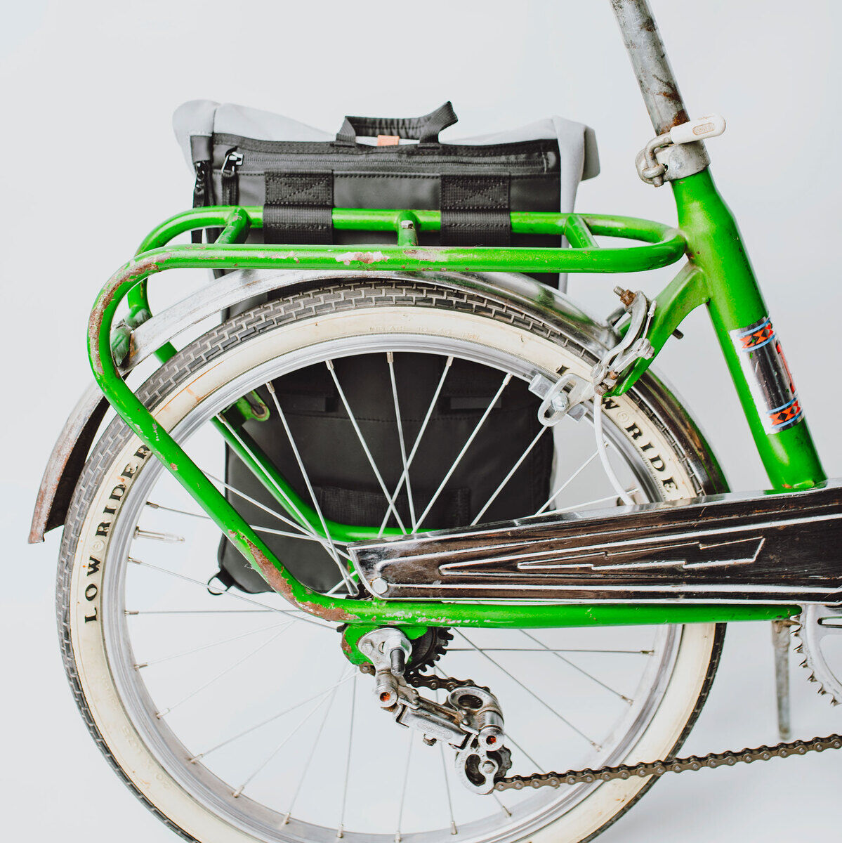 Fahrradtasche/Rucksack »Annecy« befestigt auf einem grünen Fahrrad mit Gepäckträger. Weiße Wand im Hintergrund.