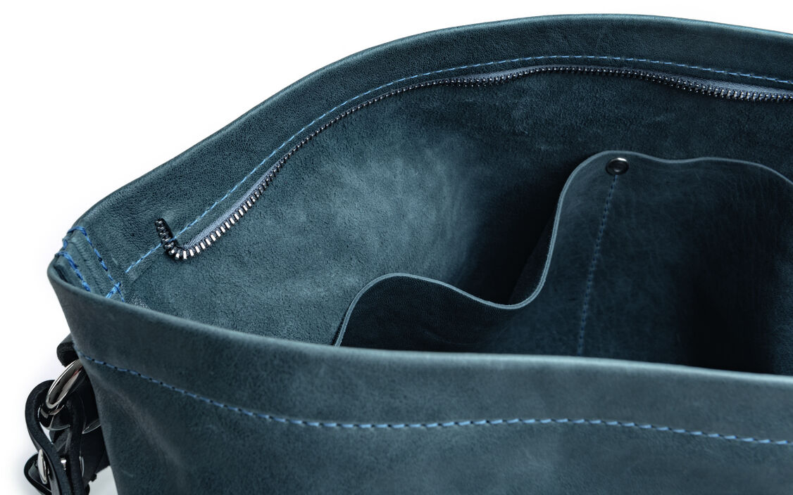 Eine hochwertige Pouch namens »Nabuko«, aus Leder gefertigt, mit einem Reißverschluss und mehreren Fächern im Inneren. Die Hauptfarben sind Blau und Schwarz, und das Design wirkt elegant und zeitlos.