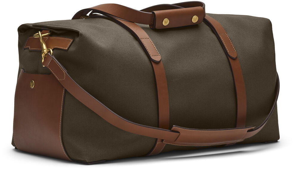 Eine elegante, dunkelgrüne Reisetasche der Marke 'SUPPLY'. Die Tasche ist aus robustem Canvas-Stoff gefertigt und hat braune Leder-Akzente an den Griffen und Trägern. Goldene Metallverschlüsse und Nieten verleihen der Tasche eine hochwertige Optik. Sie verfügt über einen langen Schulterriemen und zwei kurze Tragegriffe.