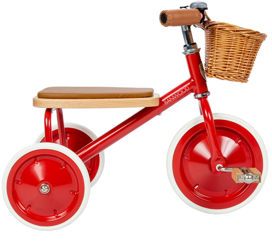 Ein rotes Retro-Dreirad mit weiß umrandeten Rädern, einer hölzernen Sitzfläche und einem kleinen Weidenkorb am Lenker.