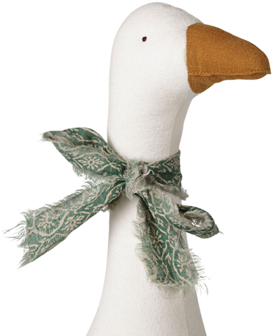 Freigestelltes Maileg-Kuscheltier in Form einer sitzenden weißen Gans. Der weiche, leicht strukturierte Stoffkörper hat gestickte Flügelkonturen, einen langen Hals, winziges dunkles Auge sowie orangebraunen Schnabel und Füße. Um den Hals ist eine ausgefranste grün-beige gemusterte Schleife gebunden.