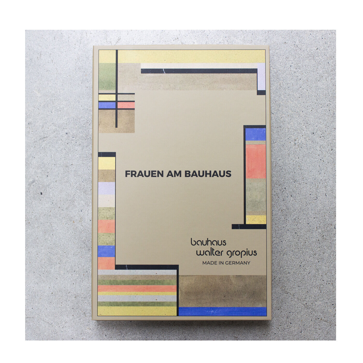 Die Verpackung der ZEIT-Sonderedition Uhr »Frauen am Bauhaus« Mint zeigt ein geometrisches, bunt akzentuiertes Bauhaus-Muster auf beigem Grund. Zentral steht der Titel in Schwarz, darunter Logos von Bauhaus und Walter Gropius sowie "Made in Germany".