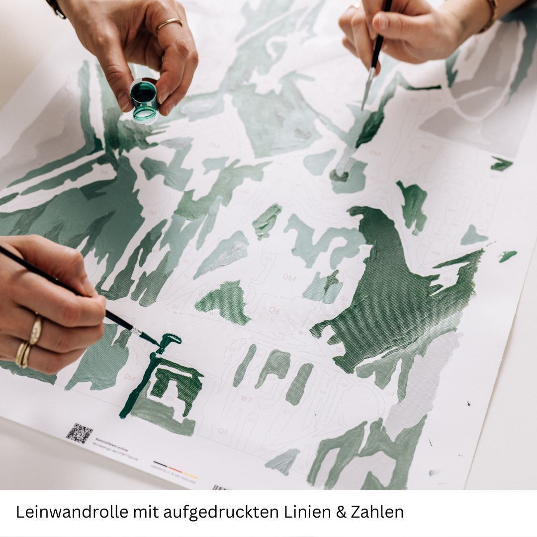 Zwei Hände, die ein Malen nach Zahlen Projekt auf einer Leinwand mit dem Titel 'Schmeckt Oysters Gut' ausmalen. Die Leinwand ist mit gedruckten Linien und Zahlen versehen, um die Malbereiche anzuzeigen. Dabei werden verschiedene Grüntöne verwendet.