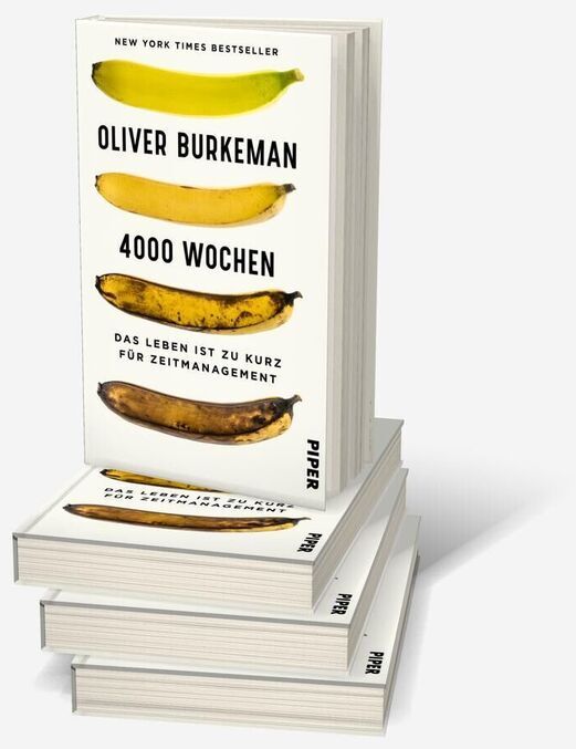 Ein Stapel des Buches '4000 Wochen' von Oliver Burkeman. Das Buch hat ein weißes Cover mit vier gelben Bananen und schwarzem Text.