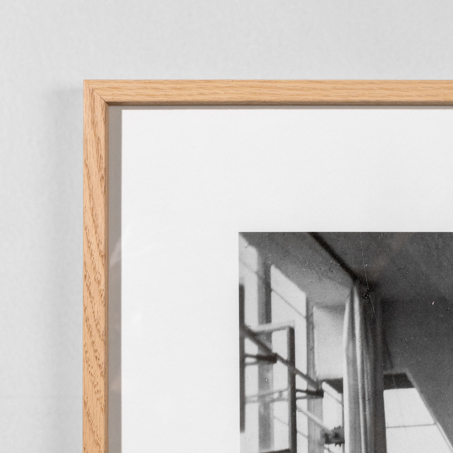 Fotografie des Bauhaus Archiv Berlin aus dem Jahr 1928 im minimalistischen Rahmen. Das Motiv zeigt lichtdurchflutete geometrische Strukturen in schwarz-weiß. Das Bild ist modern und reduziert gehalten und eignet sich als stilvolle Wanddekoration für kunstinteressierte Menschen.