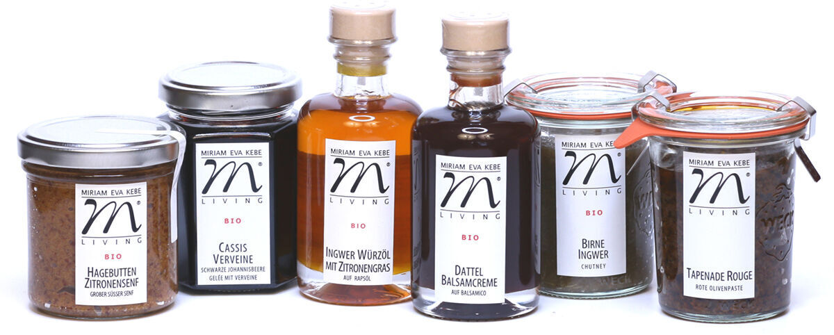 Das Bild zeigt ein Gourmet-Set »ZEIT für feine Kost«, bestehend aus einer Auswahl verschiedener Feinkostprodukte in Gläsern und Flaschen. Es umfasst Bio-Nuss-Nougat-Creme, Date-Balsamico-Essig, Cassis-Verveine-Gelee, Hagebutten-Limetten-Marmelade, einen französischen Kräutersenf, und ein Glas Tapenade Rouge.