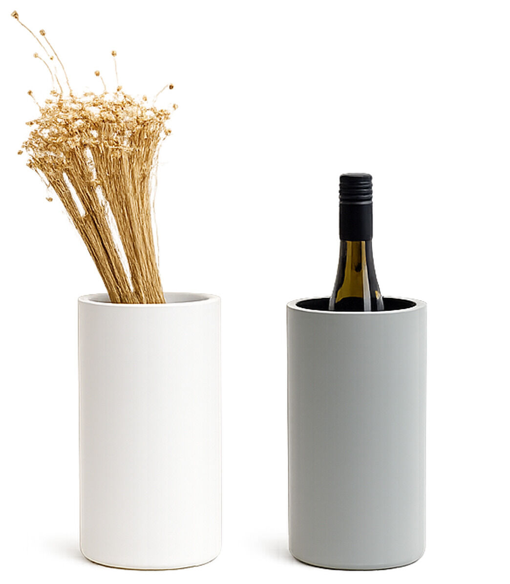 Zwei zylindrische Behälter aus Porzellan von Frau Caze: Links eine Vase in Weiß mit getrockneten Gräsern, rechts ein betongrün matter Weinkühler mit einer Weinflasche. Modernes, minimalistisches Design, glatte matte Oberfläche, klarer Hintergrund.