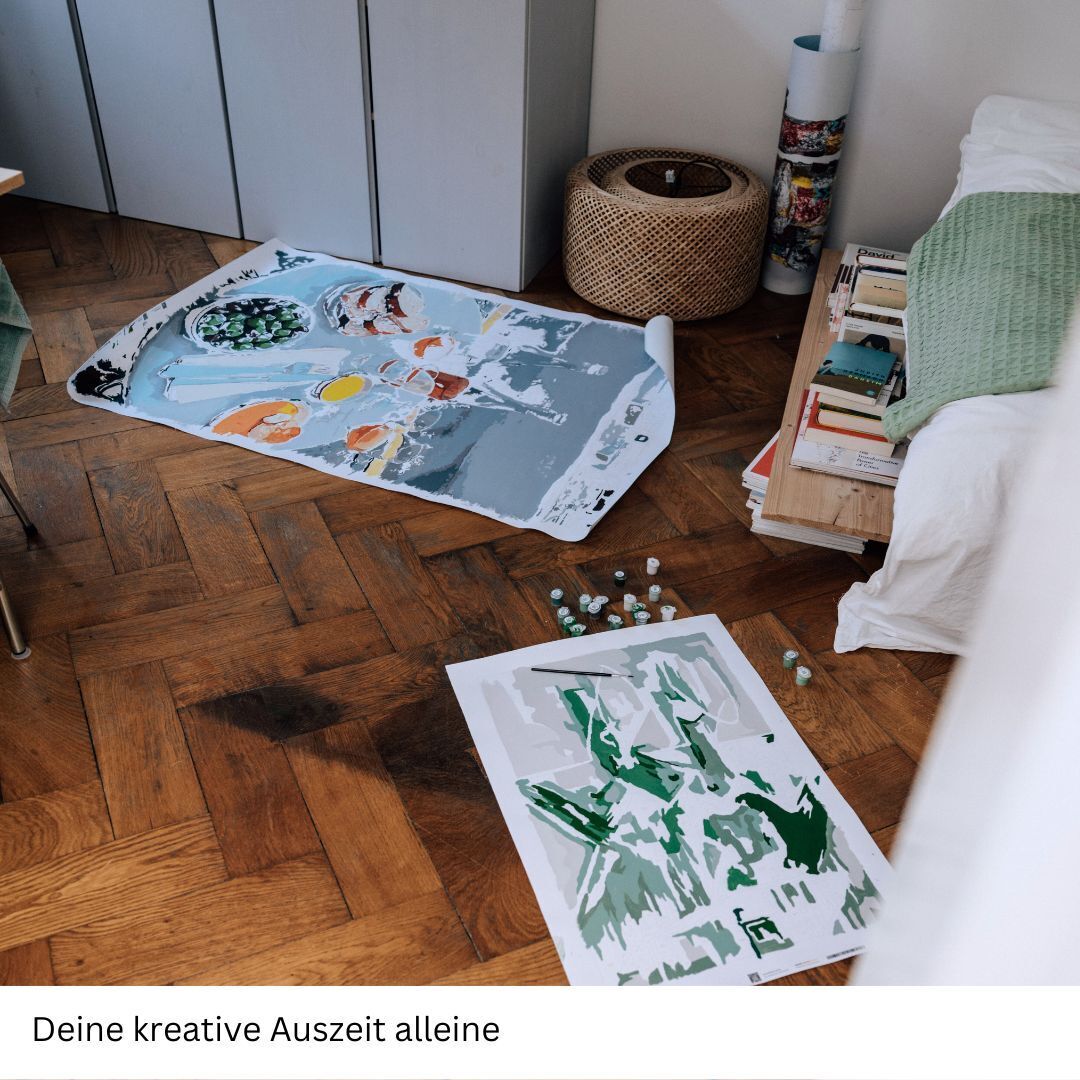 Eine Szene eines Zimmers, in dem auf dem Boden eine begonnene Malen-nach-Zahlen-Leinwand mit einem Austern-Motiv liegt. Ein Teil ist bereits in Grüntönen und Grautönen bemalt. Auf dem Boden liegen Farbtöpfe und Pinsel. Die Möbel umfassen ein Bett, einen Schreibtisch und Regale mit Büchern.