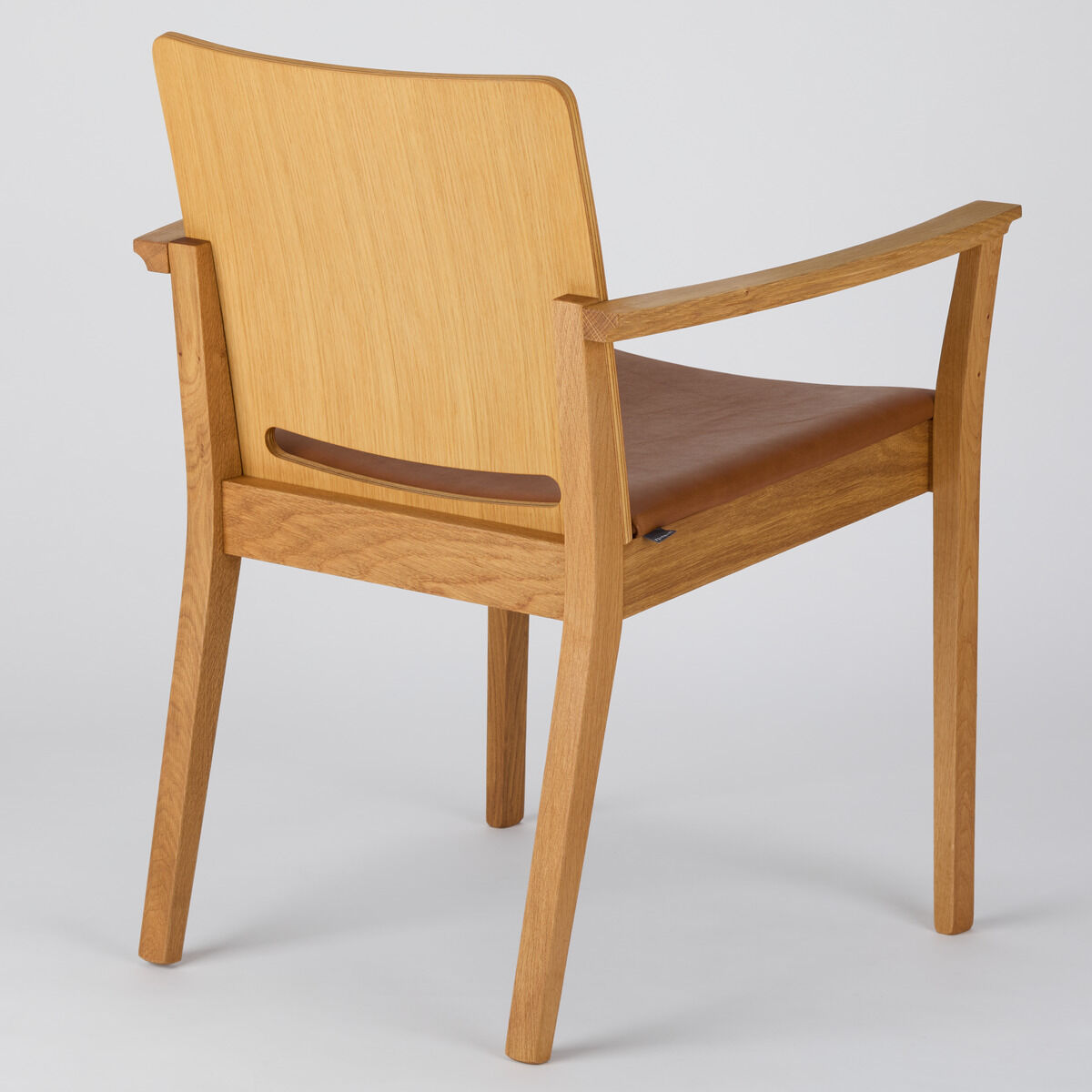 Ein moderner Armlehnstuhl mit einem Rahmen aus hellem Holz und einer braunen Sitzfläche, der einen minimalistischen und eleganten Stil verkörpert.