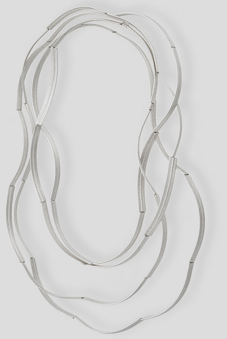 Filigrane, dreifach gelagerte Kette »Bogen« aus feinem Silber, gestaltet von Franziska Rappold. Der Schmuck besteht aus sanft gebogenen Elementen, die zu einer eleganten, schlichten Halskette verbunden sind. Das Design wirkt modern und zeitlos; Hintergrund einfarbig hellgrau.