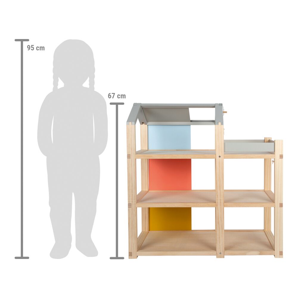 Ein modernes Puppenhaus aus Holz mit drei offenen Ebenen und farbigen Rückwänden in Blau, Grau, Rot und Gelb. Das Haus ist mit Möbeln ausgestattet und steht neben einer Größenvergleichsgrafik eines Kindes. Geeignet für Kinder zum kreativen Spielen und Einrichten.