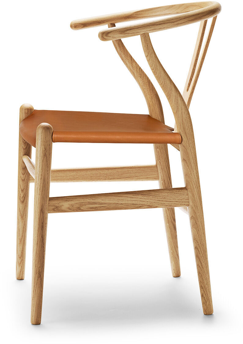 Der ZEIT Sonderedition »CH24« Wishbone Chair ist ein eleganter Designstuhl aus Eichenholz und Leder mit einem skandinavischen Touch. Der Stuhl hat eine geformte Rückenlehne aus Holz und eine Sitzfläche aus braunem Leder.