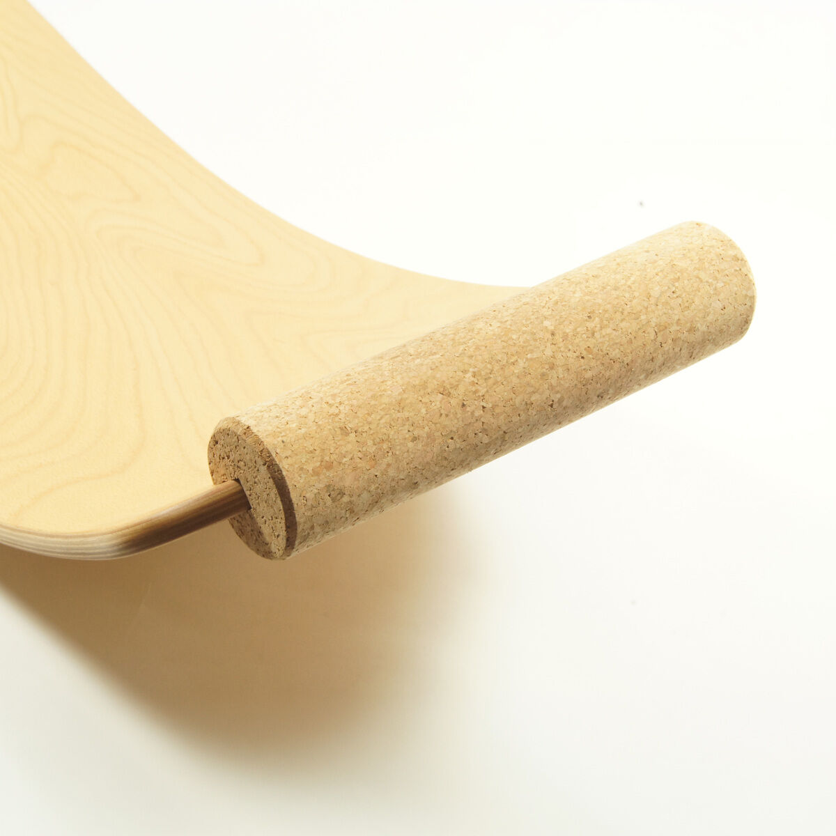 Detailaufnahme eines Balance Boards aus hellem Holz mit einer fest montierten Rolle aus Kork als Handgriff von TicToys. Die Korkrolle schützt den Boden und bietet Halt beim Turnen oder Yoga. Freundlicher, kontrastreicher Hintergrund, Fokus auf Naturmaterialien.