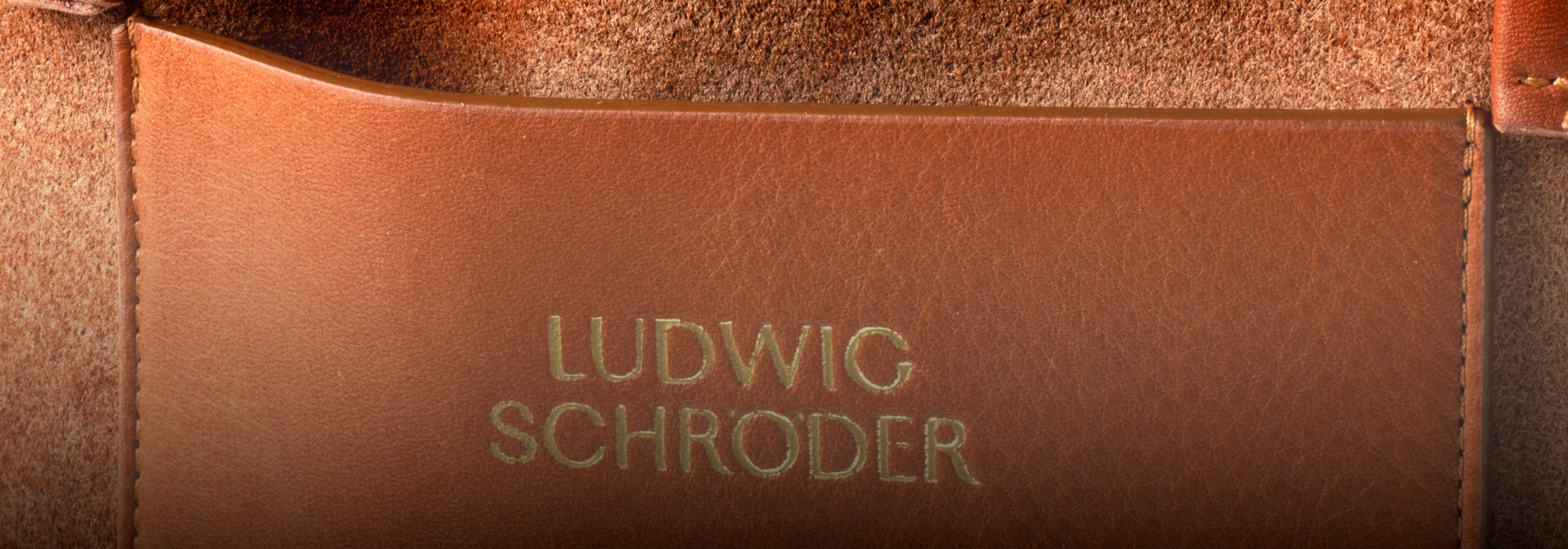 Nahaufnahme eines Lederetiketts mit der Prägung „Ludwig Schroder“, das eine reiche Struktur und warme Brauntöne aufweist.