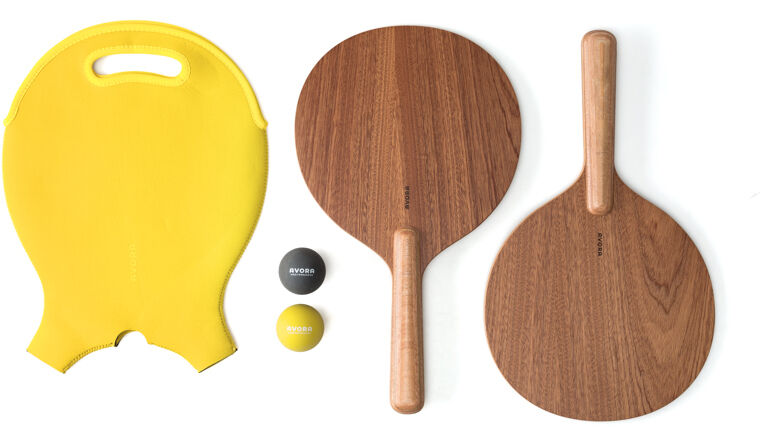 Strandball Set bestehend aus zwei Holzschlägern, einem gelben Ball und einem schwarzen Ball, und einem gelben Schaumstoff-Knieschoner