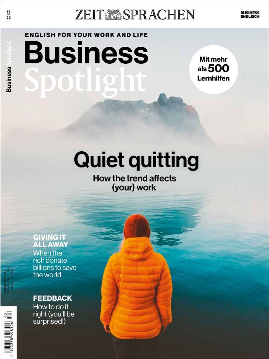 Ein Cover des Magazins Business Spotlight 12/2022. In der Mitte des Covers befindet sich eine Person in einer orangen Jacke, die auf einen nebligen See blickt. Oben steht der Titel 'Business Spotlight' und Texte zu den Themen 'Quiet quitting', 'Giving it all away' und 'Feedback'. Das Cover wird von den Farben Blau, Orange, Grau, Weiß und Schwarz dominiert.