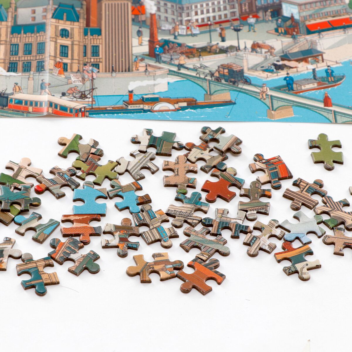 Das Bild zeigt zahlreiche Puzzleteile eines 1000-Teile-Puzzles mit Motiven aus Shakespeares London. Im oberen Bereich ist ein farbenfrohes Panorama einer historischen Stadt zu sehen, darunter liegen ausgebreitete, gemischte Puzzleteile auf weißem Untergrund.