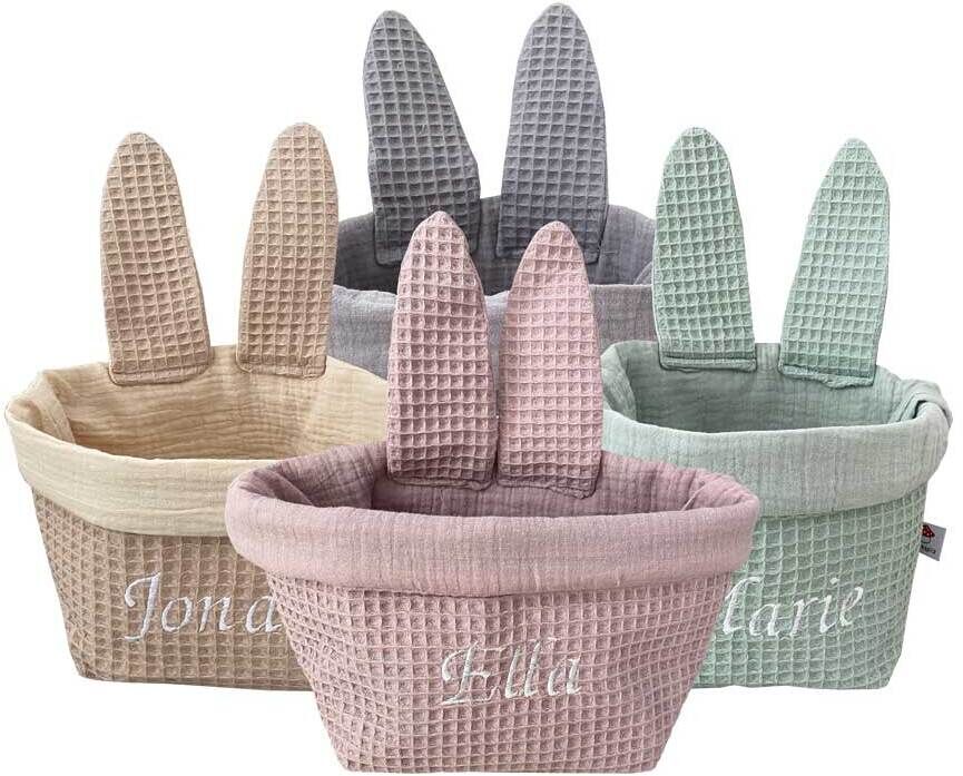 Fünf Osterkörbchen in Form von Hasenohren in verschiedenen Farben (Beige, Grau, Rosa, Mint, Lila). Die Körbchen sind aus textilen Materialien gefertigt und haben personalisierte Namen aufgestickt.