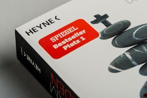 Nahaufnahme des Buches 'Karsten Dusse: Achtsam morden' mit dem Aufkleber 'Spiegel Bestseller Platz 1' und dem Heyne Verlag Logo.