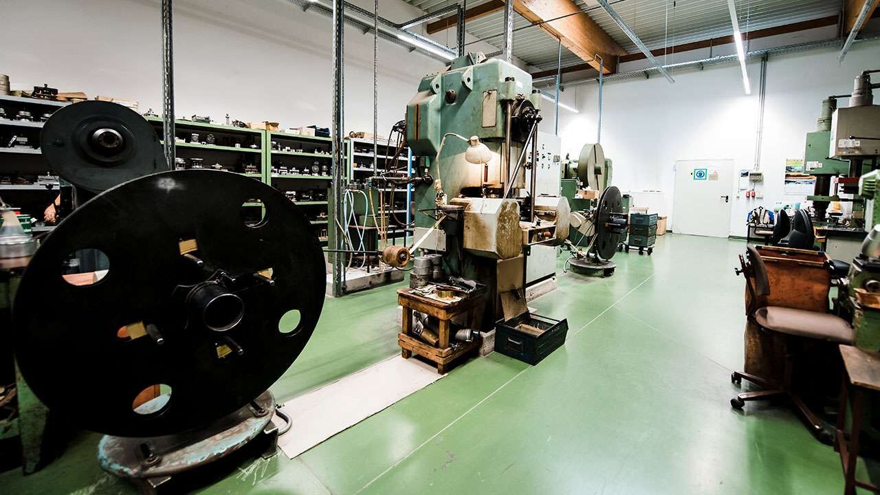 Industrielle Ledermaschinen in einer Werkstatt mit grünem Boden und Regalen im Hintergrund