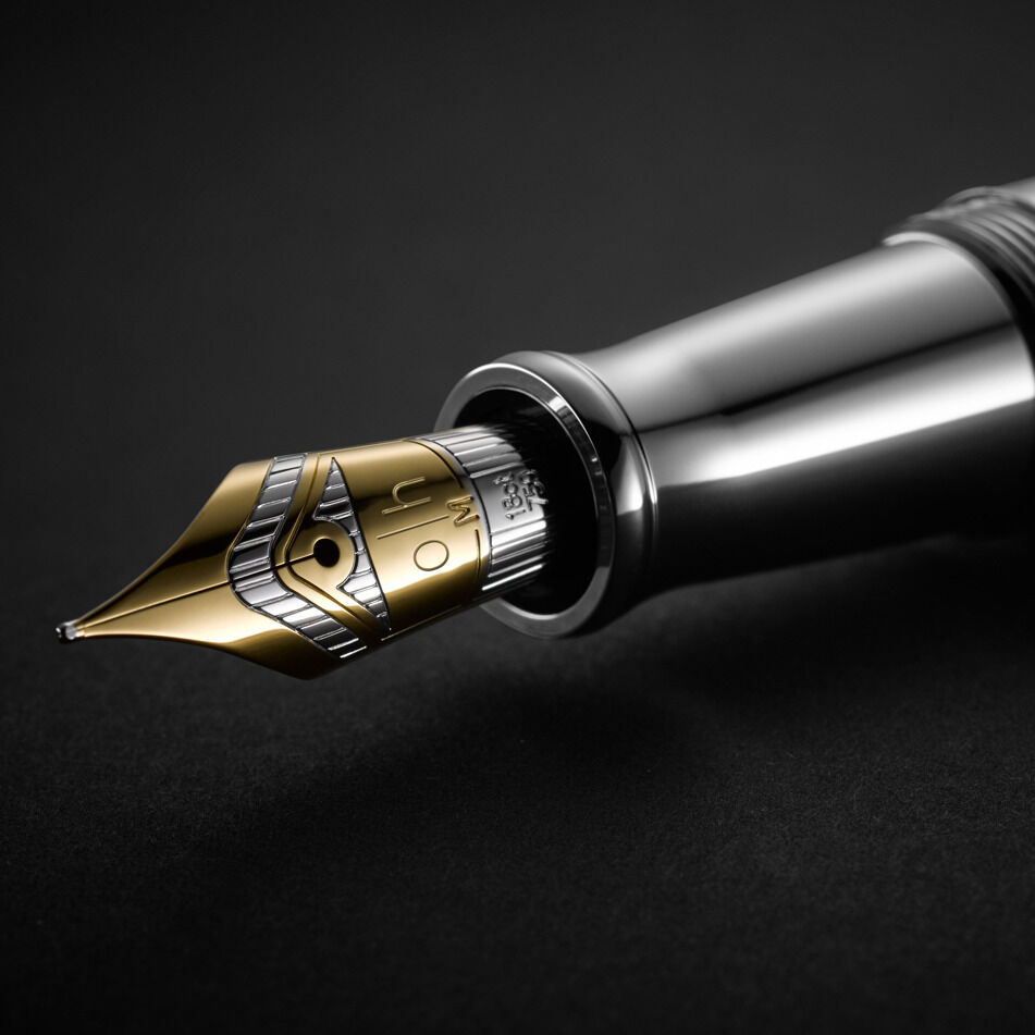 Eine Nahaufnahme eines Füllfederhalters der ZEIT-Sonderedition »Design04« in Silber und Goldtönen. Die Spitze des Stifts ist scharf fokussiert und zeigt feine Gravuren und Details.