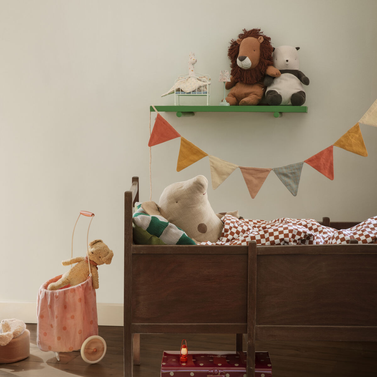 Ein Safari Freunde Kuscheltier »Löwe« sitzt dekorativ auf einem Regal in einem Kinderzimmer, das mit Wimpelketten und Spielzeugen dekoriert ist. Ein Bett ist ebenfalls im Bild zu sehen.